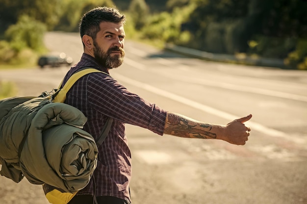 Foto uomo con zaino in autostop su strada