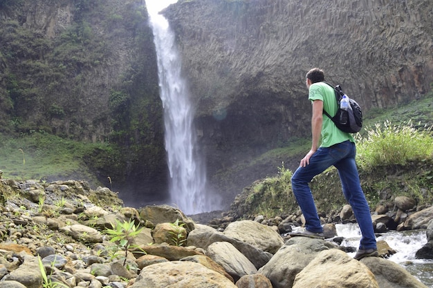 Banos de Agua Santa Cascada Manto de la Novia Banos의 폭포 앞에 배낭을 메고 서 있는 남자