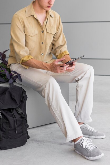 Photo man with backpack looking at tablet outdoors