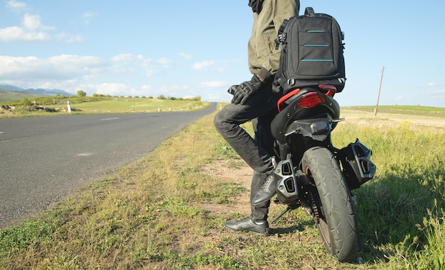 アウトドアでバックパックとバイクを持った男冒険と旅行の準備ができて