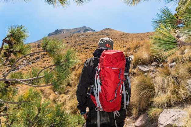 バックパックを背負った男が動機付けと目標達成を象徴する山の頂上を観察している