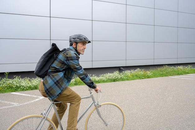 Man with backpack riding bicycle in street