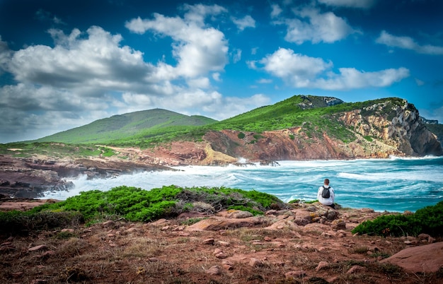 Man with backpack staring at the coast