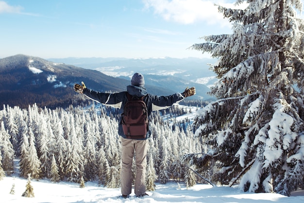 Uomo con zaino da trekking in montagna. tempo freddo, neve sulle colline. escursioni invernali. l'inverno sta arrivando, prima nevicata. concetto di viaggio, riposo, relax