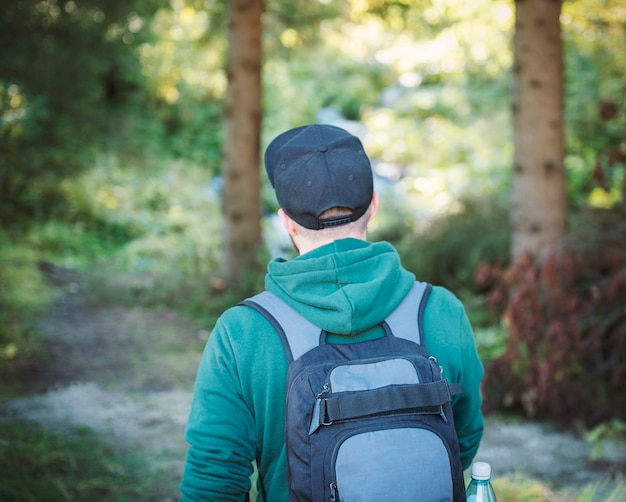 A man with backpack walks in the  autumn forest. Hiking alone along autumn forest paths. Travel concept.