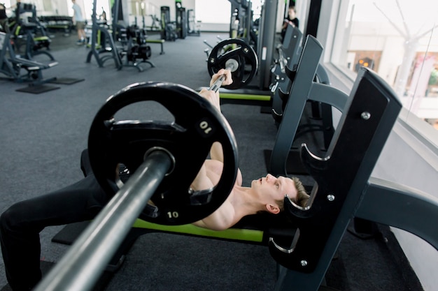 Uomo con bilanciere durante l'esercizio di panca in palestra. uomo maturo in palestra che si esercita sulla panca