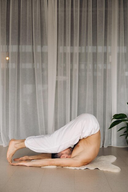 A man with a bare torso does yoga in a fitness room the concept of a healthy lifestyle