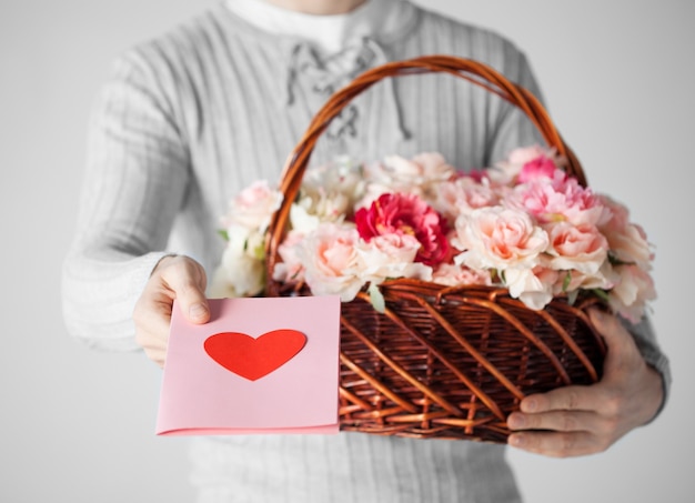 man with basket full of flowers and giving postcard.