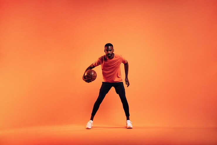 Photo man with basketball standing against orange background
