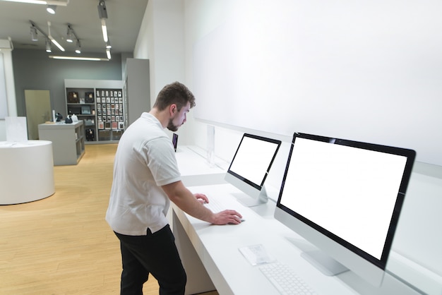 man with a beard chooses a computer at an electronics store.