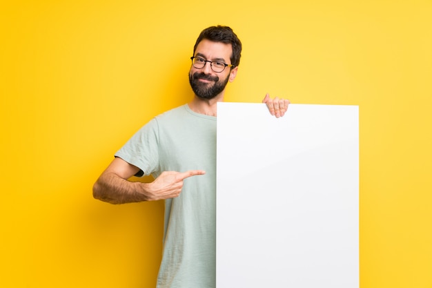 Man with beard and green shirt holding an empty placard for insert a concept