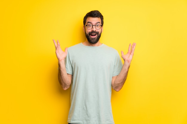 Man with beard and green shirt with surprise and shocked facial expression