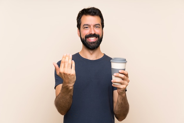 Man with beard holding a coffee inviting to come with hand. Happy that you came