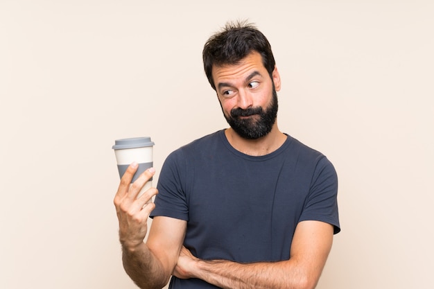 Man with beard holding a coffee with sad expression