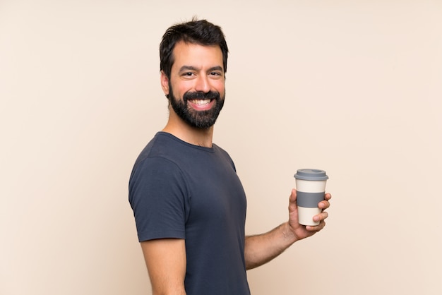 Uomo con la barba che tiene un caffè con espressione facciale di sorpresa