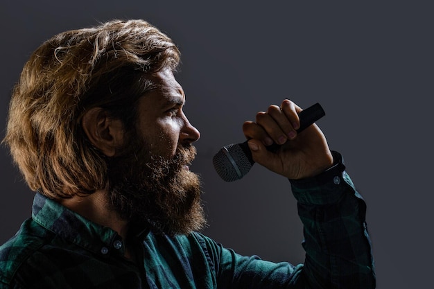 Man with a beard holding a microphone and singing Bearded man in karaoke sings a song into a microphone Male attends karaoke Bearded man singing with microphone Male singing with a microphones