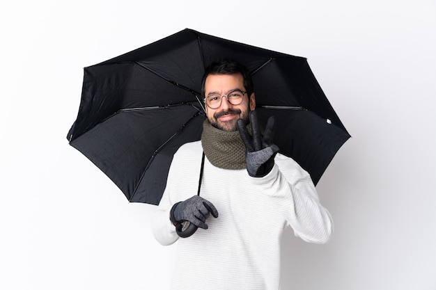 Man with beard holding umbrella over isolated wall