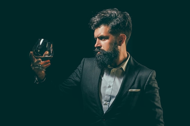 Man with beard holds glass brandy degustation and tasting sipping whiskey