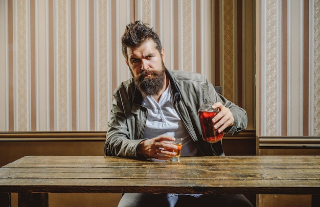 Man with beard holds glass brandy man holding a glass of whisky handsome stylish bearded man is drin...