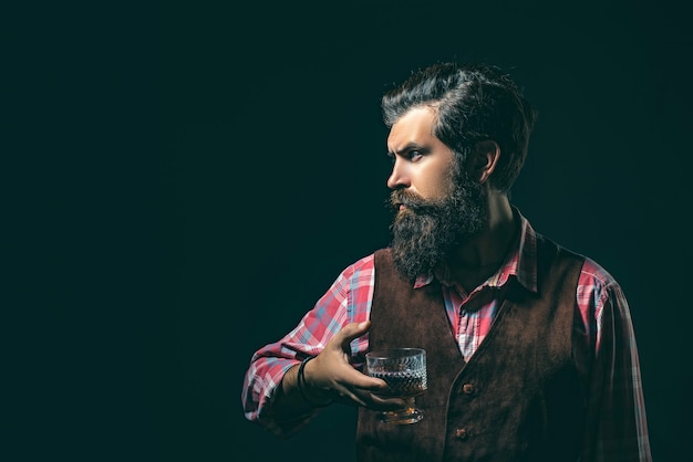 Foto l'uomo con la barba tiene il brandy di vetro elegante l'uomo con la barba il barista tiene il bicchiere di whisky sommelie...