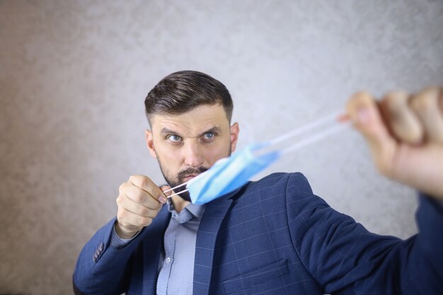 a man with a beard and a jacket is holding a medical mask