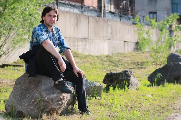 A man with a beard and in jeans stands in the industrial zonexA