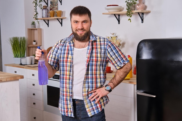 Un uomo con la barba in cucina ha deciso di prendersi una pausa e di scherzare con uno spruzzatore nel suo...