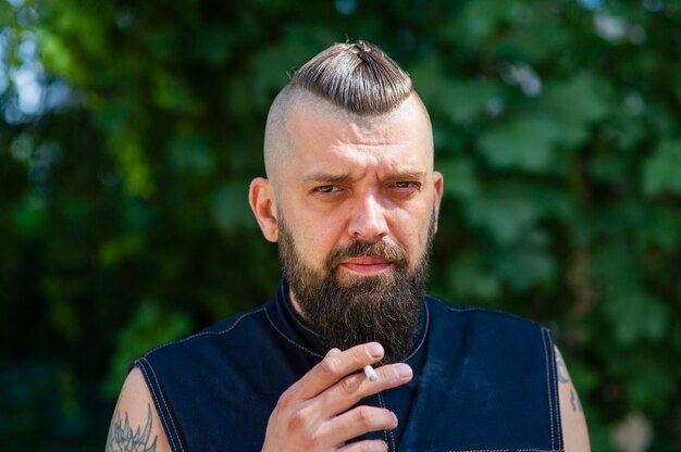 Man with beard and mustache holding a cigarette.