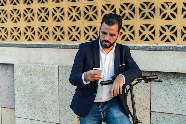 A man with a beard and a scooter checking his phone