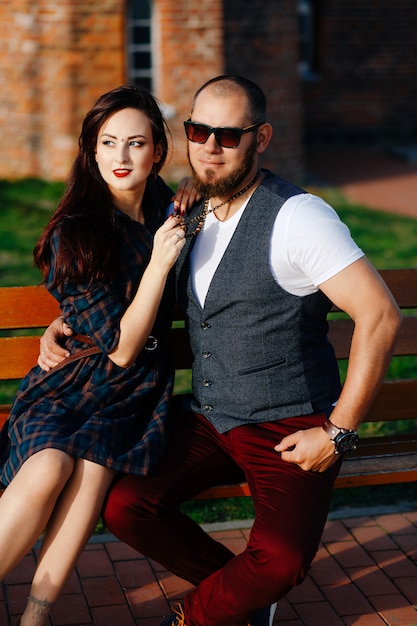 a man with a beard sits on a bench with a beautiful woman