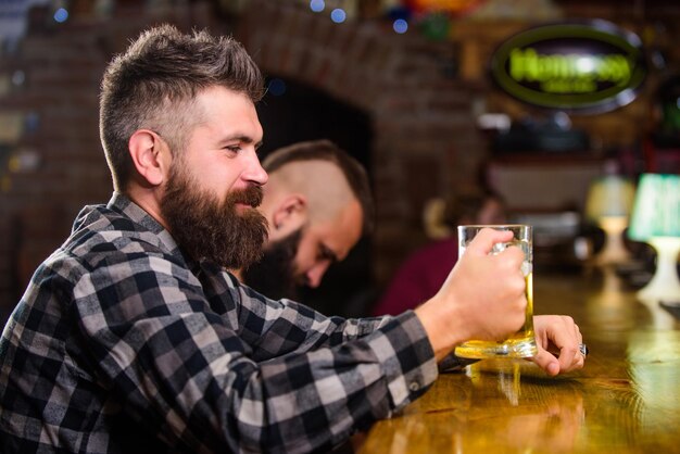 Man with beard spend leisure in dark bar brutal hipster bearded
man sit at bar counter drink beer order alcohol drink bar is
relaxing place have drink and relax hipster relaxing at bar with
beer