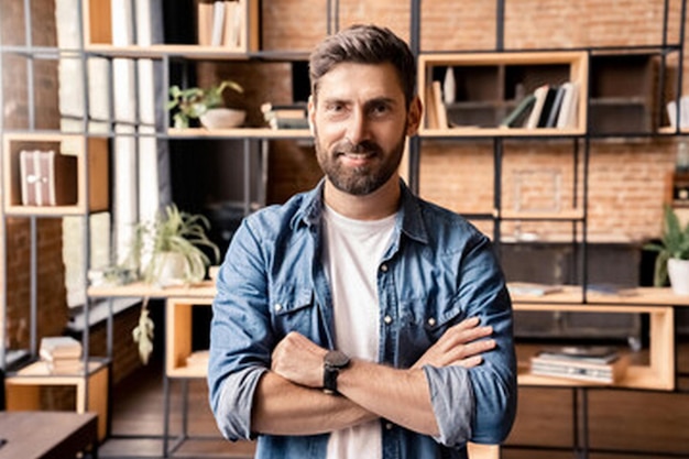 a man with a beard stands in front of a book shelf