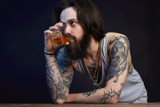Man with beard and tattoo man drink whiskey