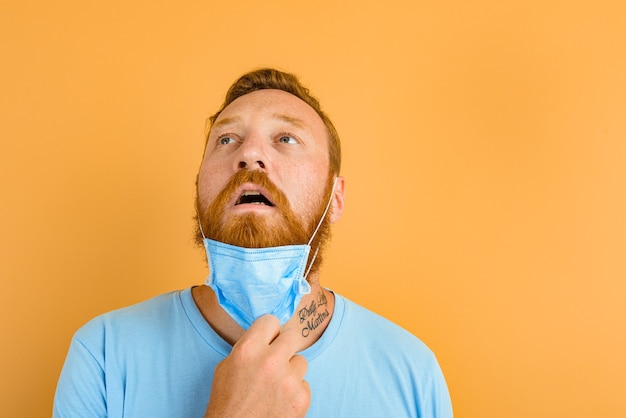 Man with beard and tattoos removes the mask for covid