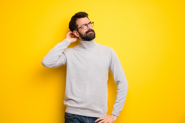 Man with beard and turtleneck having doubts while scratching head