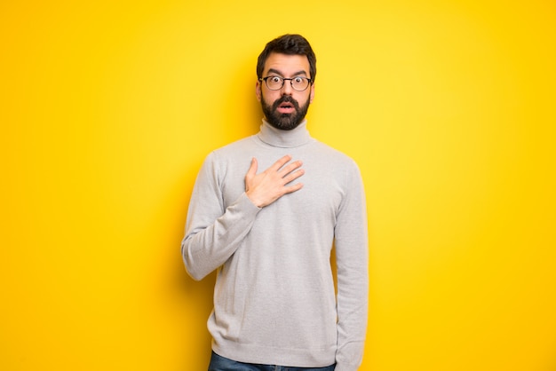 Man with beard and turtleneck surprised and shocked while looking right