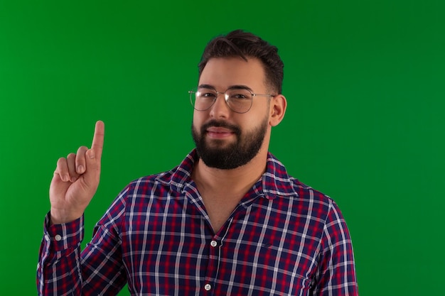 Photo man with a beard wearing glasses and a plaid shirt in a studio photo with a green background ideal for cropping