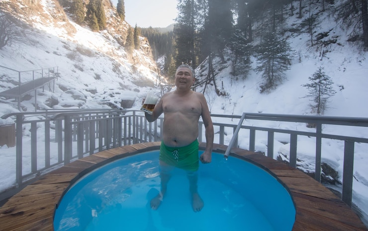 Photo man with a beer in hot baths with thermal waters in the mountains in winter