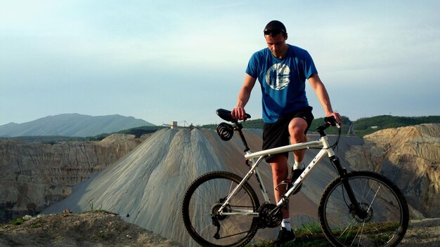 Photo man with bicycle on mountain against sky