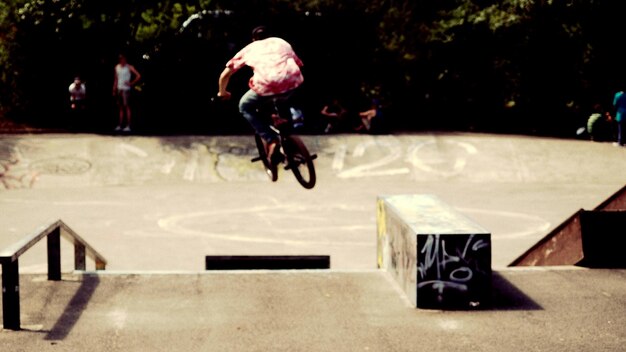 Photo man with bicycle performing stunt on sunny day