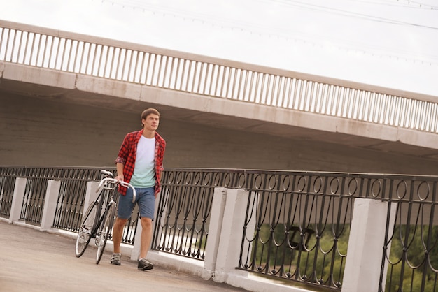 Uomo con la bicicletta che cammina sulla banchina