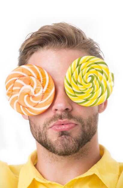 Man with big lollipops with hypnotizing pattern on eyes as eyeglasses. Hypnotized concept. Guy on calm face with giant colorful lollipops, isolated on white background. Man with bristle likes sweets.