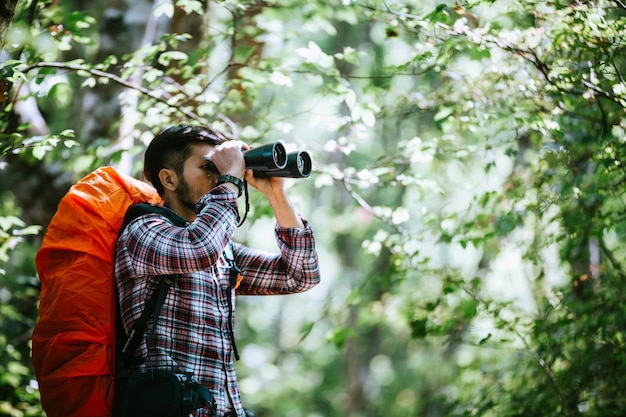 Man with Binoculars and Telescope in Rain Forest.