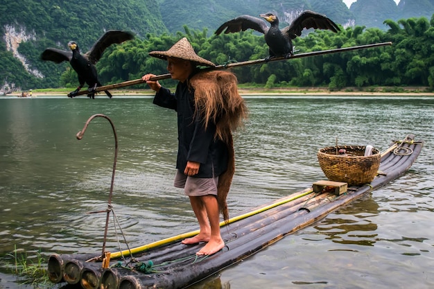 Foto uomo con uccelli su zattere di legno nel lago