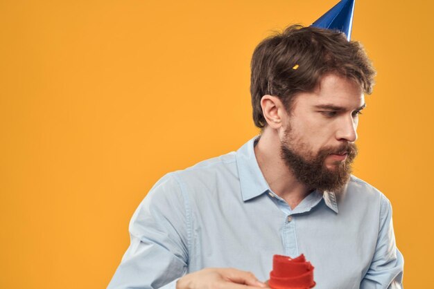 A man with a birthday cake in his hands on a yellow background birthday dessert person