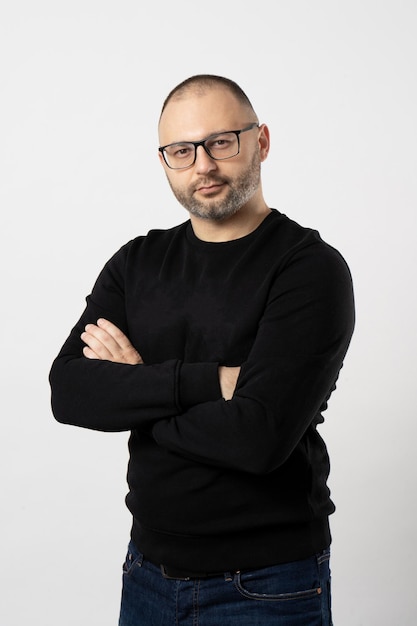 A man with black-rimmed glasses poses with his arms crossed on his chest