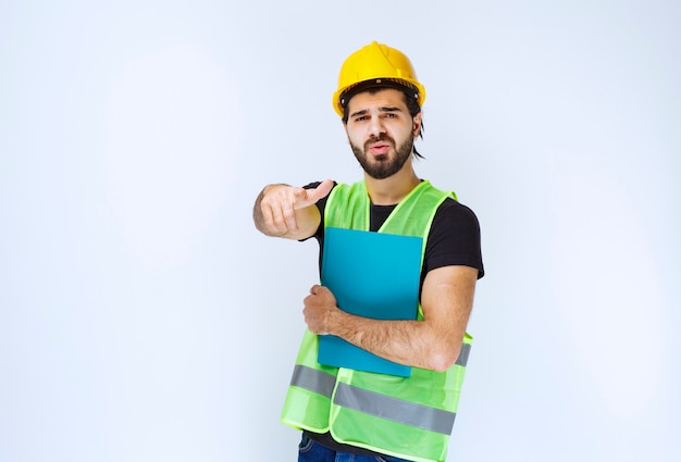 Uomo con una cartella blu che punta a qualcuno più avanti.