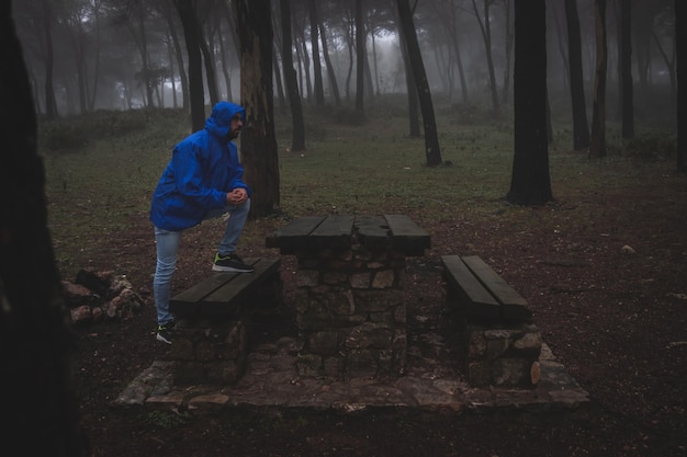 Человек с синим плащом идет через туманный лес