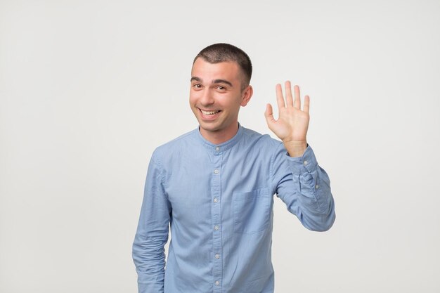 Man with blue shirt saying hello waving a hand