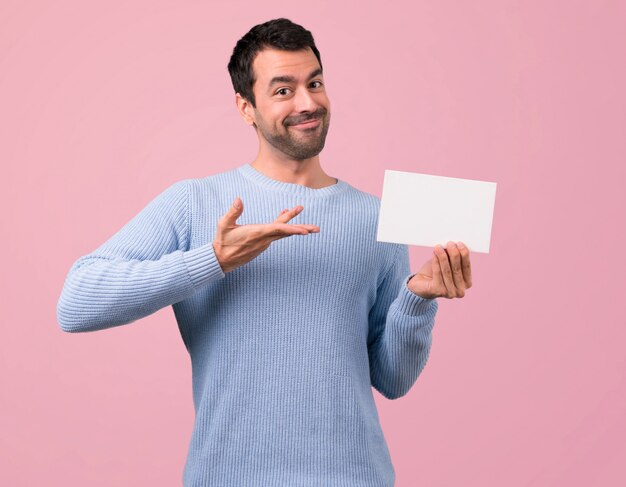 Foto uomo con maglione blu che tiene un cartello bianco vuoto